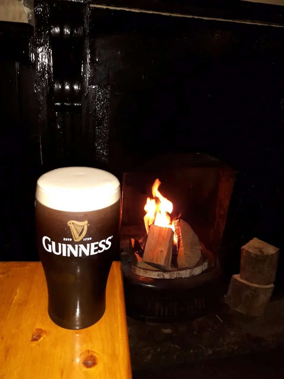 A perfectly poured pint of Guinness beside a roaring open fire at Furey's Pub